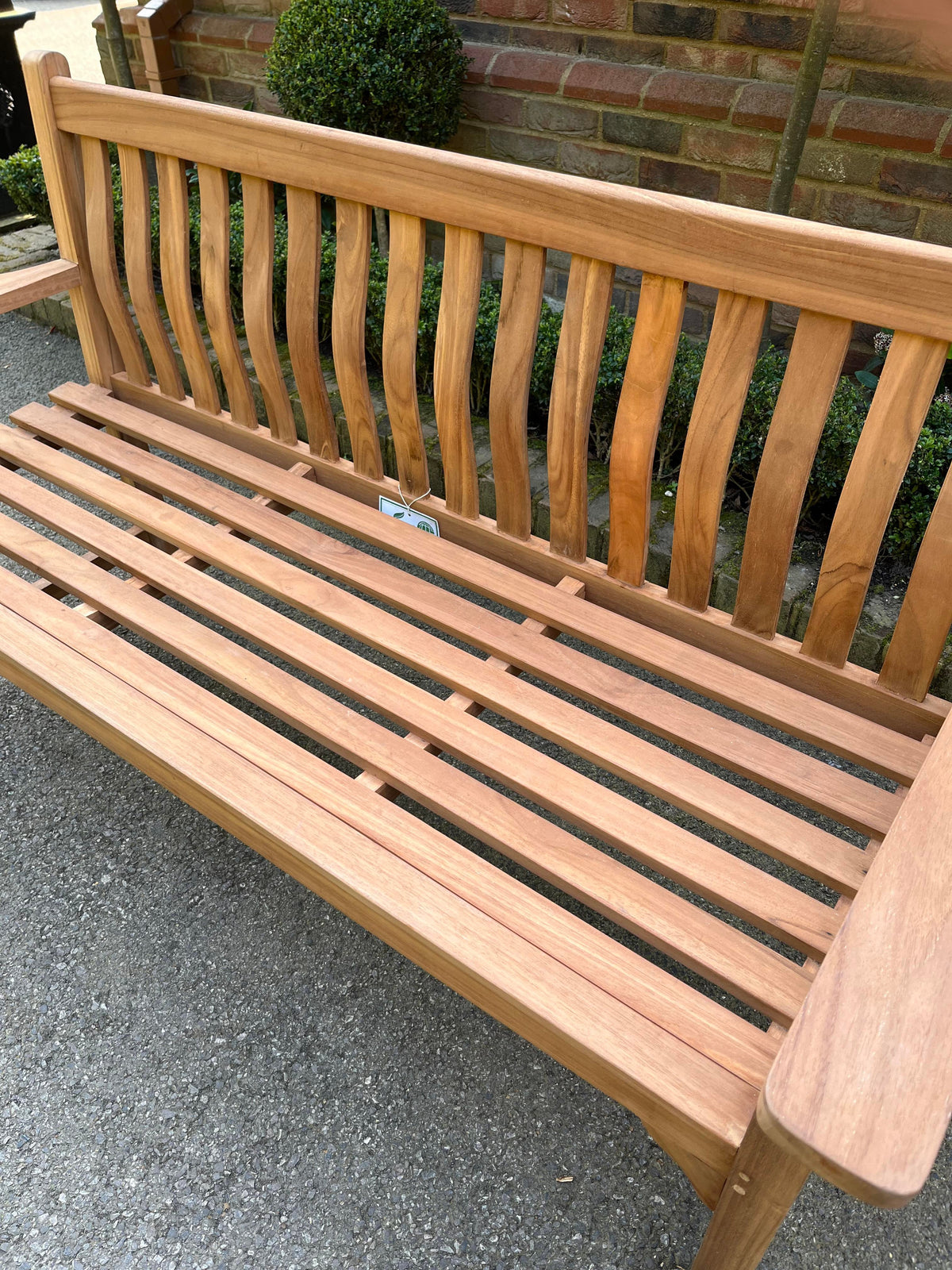 Close-up of the wave back teak bench's curved back slats and seat