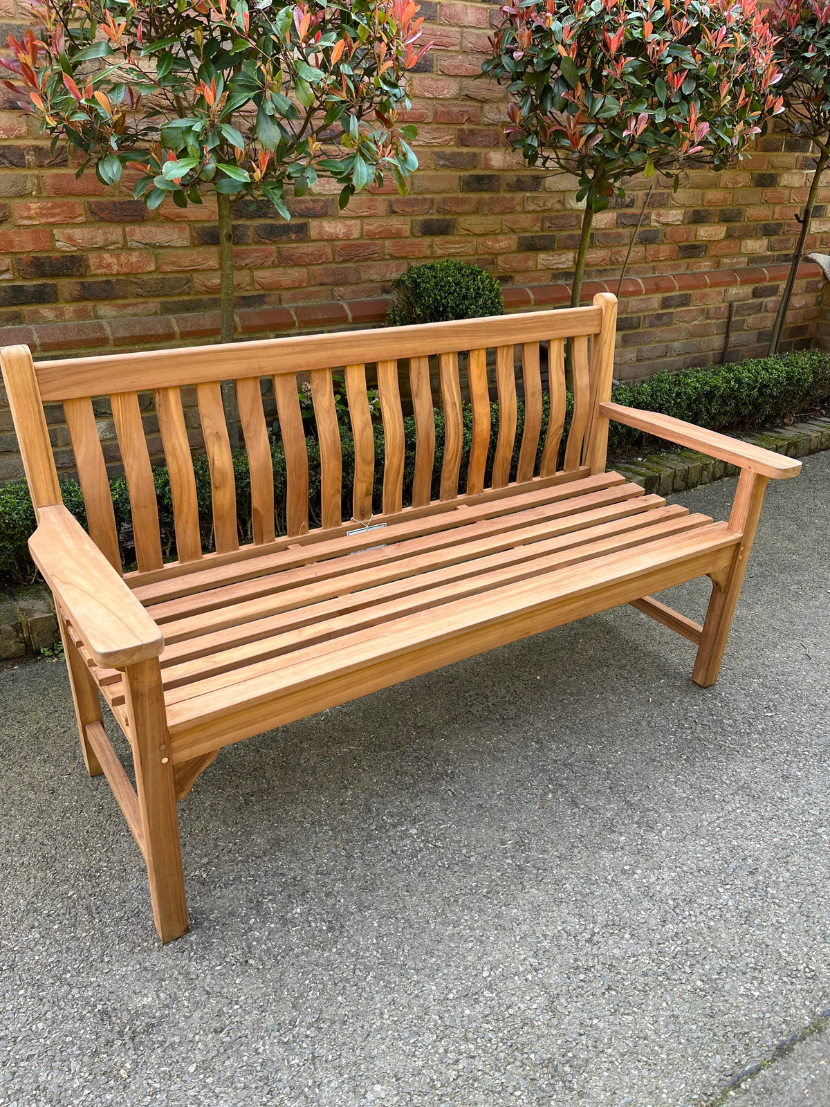 Wave back teak garden bench, 3 seater 130cm, on a patio