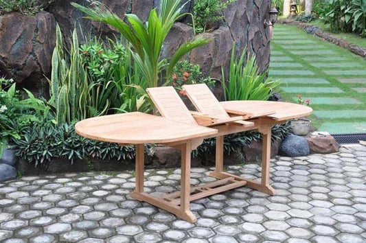 Classic oval double leaf teak extending table in a garden