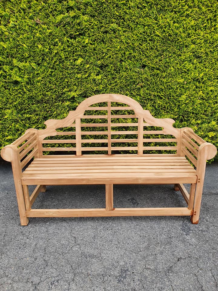 Lutyens 3 seater teak garden bench in front of a green hedge