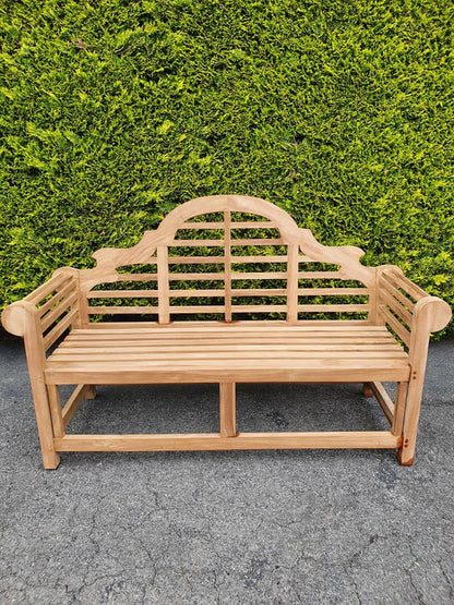 Lutyens 3 seater teak garden bench in front of a green hedge